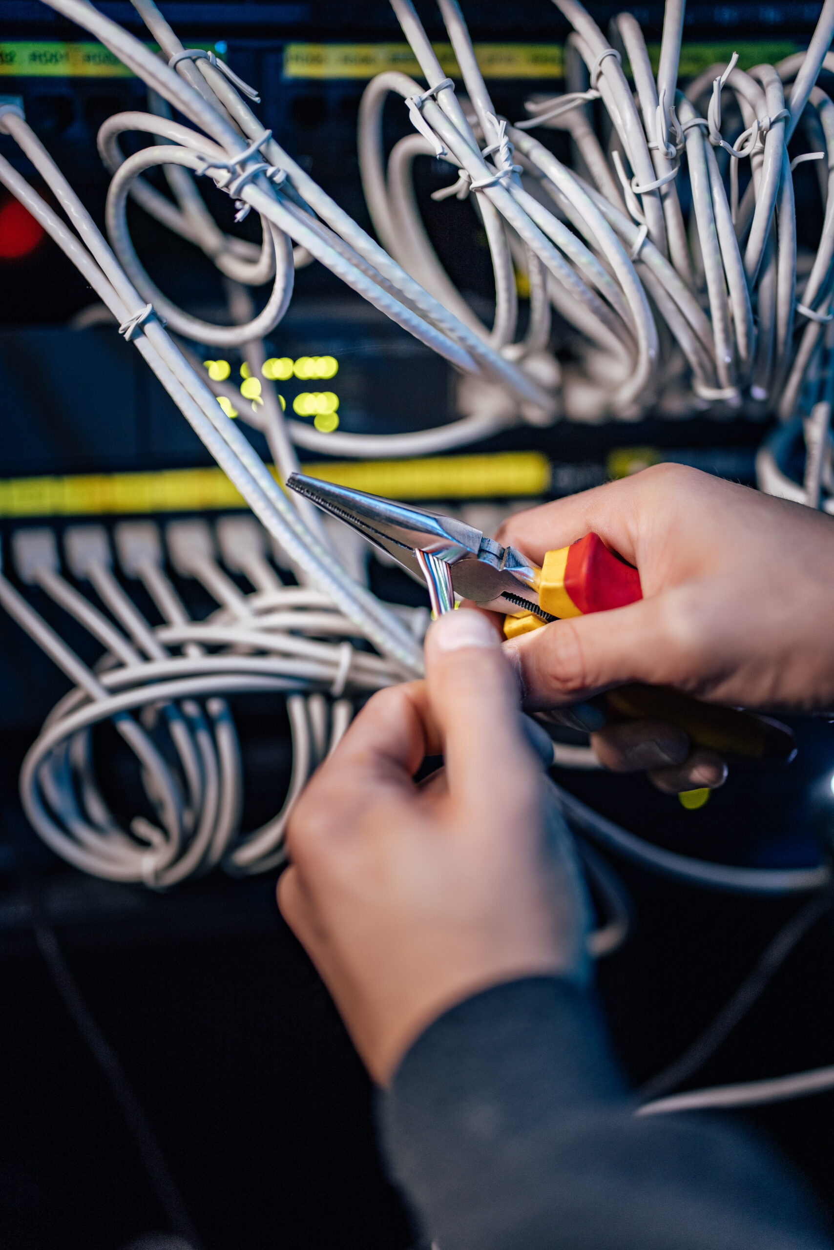 Technik wykonujący okablowanie sieci LAN przy patch panelu